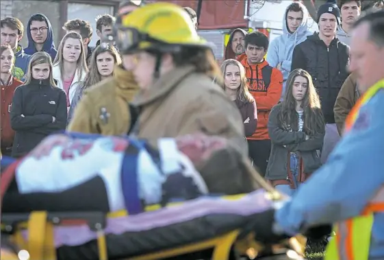  ?? Steve Mellon/Post-Gazette photos ?? Students at Avonworth High School watch rescue workers extract “victims” from a mock automobile crash Monday in the parking lot of the school in Ohio Township. The portrayal was designed to deter students from getting behind the wheel while under the...