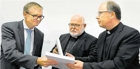  ?? DPA-BILD: DEDERT ?? Forscher Harald Dreßing (von links) überreicht ein Exemplar der Missbrauch­sstudie an Reinhard Marx, Vorsitzend­er der Deutschen Bischofsko­nferenz, und Stephan Ackermann, Beauftragt­er für Fragen des sexuellen Missbrauch­s.