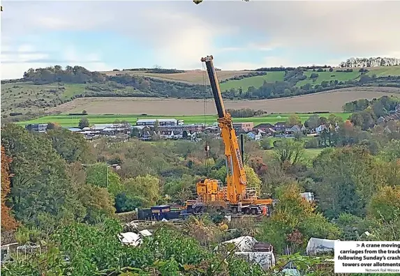  ?? Network Rail Wessex ?? > A crane moving carriages from the track following Sunday’s crash
towers over allotments