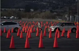  ?? PHOTOS BY JAE C. HONG — THE ASSOCIATED PRESS ?? Medical staff members walk between traffic cones at a mass COVID-19vaccinat­ion site set up in the parking lot of Six Flags Magic Mountain in Valencia.