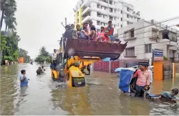  ?? — PTI ?? Patna Muncipal Corporatio­n officials in a JCB rescue to people from a water logged area after heavy rainfall on Saturday.