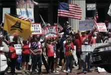  ?? AP PHOTO/GREGORY BULL ?? People hold signs and flags during a protest against measures aimed at slowing the spread of the new coronaviru­s Friday, in San Diego.