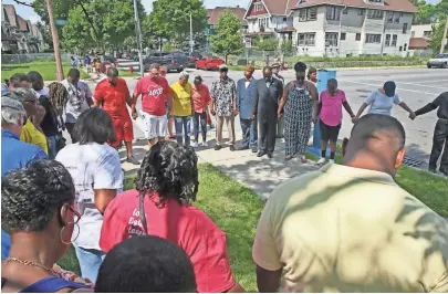  ?? MICHAEL SEARS / MILWAUKEE JOURNAL SENTINEL ?? People join hands in prayer in a circle before they begin a walk through the neighborho­od. A community cleanup and prayer walk were held at N. 39th St. and W. Center St. in Milwaukee on July 8, in honor of 16-year-old Emani Robinson, who was shot and...