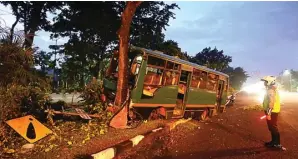  ?? GALIH COKRO/JAWA POS ?? KEBUT-KEBUTAN: Bus bernopol W 7711 UY yang dikemudika­n Mianam berhenti setelah menghantam pohon yang berdiri di jalur hijau Jalan Ahmad Yani kemarin pagi (3/2).
