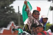  ?? Moises Castillo / Associated Press ?? Central American migrants making their way to the U.S. in a large caravan wave a Mexican flag as they arrive in Tapachula, Mexico, after a truck driver gave them a free ride on Sunday.