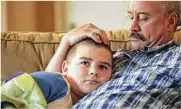  ??  ?? Brayden’s dad, Jeff, comforts him on the morning of the surgery as the two watch “The Today Show.”