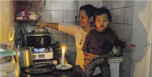  ?? Jordi Otix ?? La familia Espino, con un niño pequeño, cocina con gas butano y a la luz de una vela en su piso del Raval.