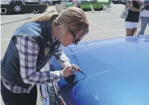  ??  ?? Beth Kearney, a self-taught pinstriper from Loveland, Colo., puts a design on a 1963 Chevry at the Vegas show. It was a hobby that’s become a career.