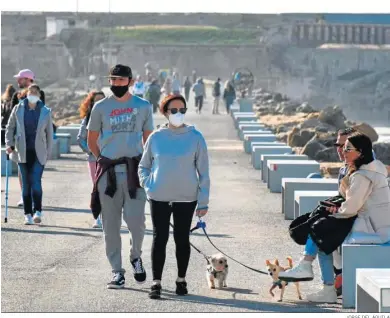  ?? JORGE DEL ÁGUILA ?? Varias personas pasean con mascarilla­s por el camino de acceso a la isla de Tarifa.