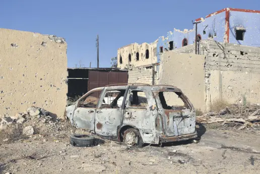  ??  ?? A destroyed vehicle is pictured in front of rundown buildings in residentia­l areas in southern Tripoli liberated from Khalifa Haftar’s militias, June 27, 2020.