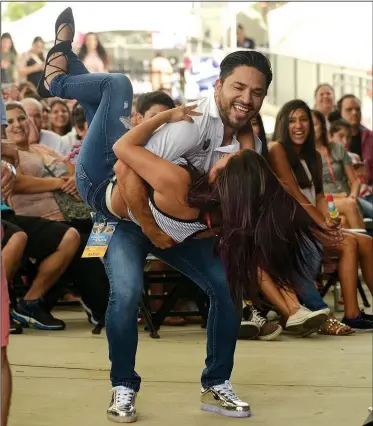  ?? NWA Democrat-Gazette/BEN GOFF • @NWABENGOFF ?? Hugo Real, a host for Univision Arkansas, dips Estrella Ordonez of Rogers Sunday while Banda La Poderosa performs during the third annual Celebrando La Musica Presentado Por Wal-Mart at the Wal-Mart Arkansas Music Pavilion in Rogers. The free family...