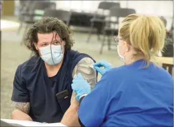  ?? H John Voorhees III / Hearst Connecticu­t Media ?? EMT Eugenia McGovern, right, from Griffin Health, gets ready to administer the first shot of Moderna vaccine to Anthony Capirichio, of Danbury, who was a walk-in to the COVID-19 vaccine clinic held in the Danbury Public Library on April 30.