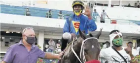  ?? (Photo: Naphtali Junior) ?? Jockey Omar Walker aboard Universal Boss celebrates completing his fifth winner at Caymanas Park, yesterday. Sharing in the occasion are (from left) trainer Anthony Nunes and groom Shamari White.