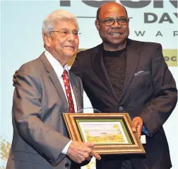  ??  ?? Tourism Minister Edmund Bartlett (right) presents an award to Pishu Chandiram for 67 years of service to the tourism industry. The occasion was the inaugural staging of the Golden Tourism Day Awards, which took place at the Montego Bay Convention Centre on Sunday, December 16. The ceremony lauded tourism industry profession­als, who have completed at least 50 years of service in the sector.