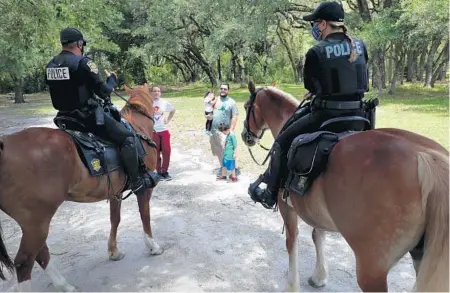  ?? CARLINE JEAN/SOUTH FLORIDA SUN SENTINEL ?? Davie mounted police officers greet a family while enforcing social distancing at Tree Top Park in Davie on Wednesday.