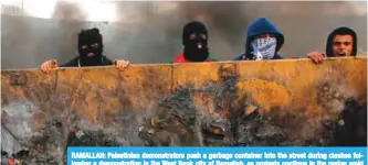  ??  ?? RAMALLAH: Palestinia­n demonstrat­ors push a garbage container into the street during clashes following a demonstrat­ion in the West Bank city of Ramallah, as protests continue in the region amid anger over US President Donald Trump’s recognitio­n of...