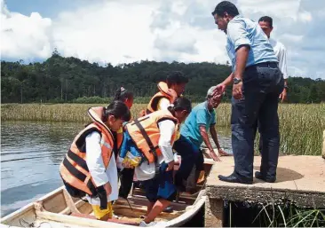  ??  ?? Roughing it out: SK Tasik Chini teachers helping their pupils to disembark from a boat they use to go to school with.