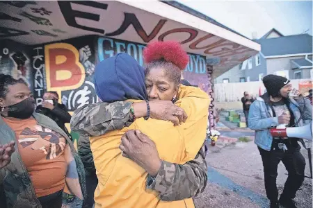  ?? MARK HOFFMAN/ USA TODAY NETWORK ?? Maria Hamilton, whose son Dontre was fatally shot by a police officer in 2014, embraces a supporter Tuesday near a mural and memorial for George Floyd in Milwaukee. The officer was fired but not prosecuted.