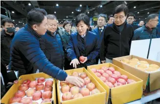  ?? Yonhap ?? Agricultur­e Minister Song Mi-ryung, center, examines apples at an auction house in Garak Market in Seoul, March 12.