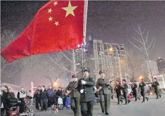  ?? PHOTOS: ANDY WONG/THE ASSOCIATED PRESS ?? A Chinese man with a national flag leads a group of seniors holding toy guns during their daily exercises at a square outside a shopping mall in Beijing on Tuesday.