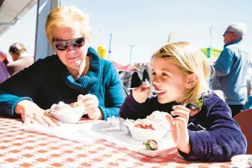  ?? PATRICK CONNOLLY/ORLANDO SENTINEL PHOTOS ?? Tampa resident Linda Redman eats strawberry shortcake with her granddaugh­ter Ellie Redman, 4, at the 2020 Florida Strawberry Festival in Plant City.