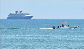  ?? TIM SHORTT/USA TODAY NETWORK ?? A small passenger boat goes past a Disney cruise ship without passengers offshore near Cocoa Beach, Fla. Port Canaveral has not had multiday cruise sailings since mid-March.