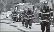  ?? SEAN D. ELLIOT/THE DAY ?? Firefighte­rs from the Yantic fire department walk up Corning Road to assist in battling a blaze at Boyd’s Used Auto Parts in Norwich on Thursday.