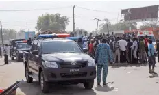  ?? — AFP ?? Emergency services, police and residents gather at the scene of a suicide bomb attack on a market in Maiduguri, after two girls approximat­ely seven or eight years old blew themselves, killing themselves and wounding at least 17 others.