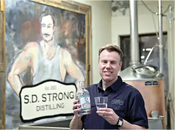  ?? AP Photo/Charlie Riedel ?? ■
Steve Strong holds a bottle of gin at his business, S.D. Strong Distilling, on Jan. 19 in Parkville, Mo. Strong is planning to hire some part-time employees and buy some equipment as a result of the new tax law.