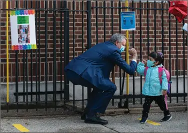  ?? (The New York Times/Todd Heisler) ?? Mayor Bill de Blasio greets a student Monday at the Mosaic Pre-K Center in the Queens borough of New York, as some students return to classrooms. Last week, de Blasio delayed in-school instructio­n for most children.