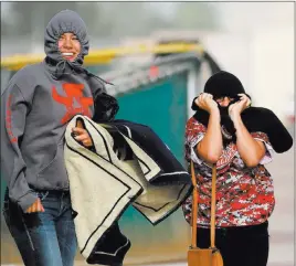  ?? RONDA CHURCHILL/ LAS VEGAS REVIEW-JOURNAL ?? Arbor View High School students Vanessa Lourenco, left, and Amaris Calderon run back to the bleachers in the wind after retrieving additional items of clothing when the weather took a turn for the worse during an Arbor View baseball game against...