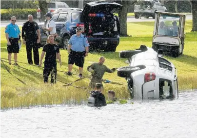  ?? TAIMY ALVAREZ/STAFF PHOTOGRAPH­ER ?? Police and tow truck operators work to get a Toyota Highlander out of a small lake in front of the Broward County Southwest Regional Library. Police said three witnesses jumped into the water, attempting to pull the driver and passenger out before...