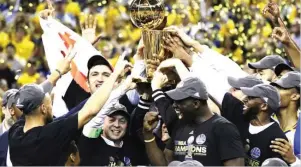  ??  ?? Golden State Warriors players, coaches and owners hold up the NBA Championsh­ip trophy following the series win on Monday night