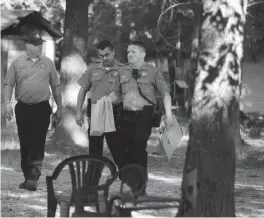  ?? Staff file photo by Jerry Habraken ?? ■ Bossier Parish, La., bomb technician Ian Snellgrove, left, speaks with Bowie County deputies Brent Caudle, center, and Adam Ball, as Ball carries a dismantled improvised explosive device or IED, from a lot Sept. 26, 2013, on Tomahawk Road.