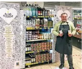  ?? FOTO: EDEKA ?? Felix Buller, Inhaber von Edeka Buller in Lichtenbro­ich, neben einem Regal mit lokalen Produkten – zum Beispiel Suppendose­n von Dauser.