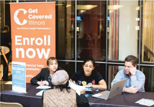  ?? MAXHERMAN/ FOR THE SUN- TIMES ?? Leticia Galvez ( center) helps a woman enroll in an Affordable Care Act insurance plan at the James R. Thompson Center on Nov. 29, 2017.