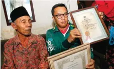  ?? DIPTA WAHYU/ JAWA POS ?? TUNJUKKAN PIAGAM PENGHARGAA­N: Soeharto (kiri) menemui Menpora Imam Nahrawi yang mengunjung­i rumahnya kemarin (24/7).