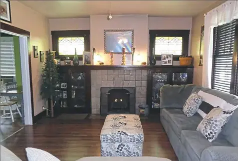  ?? Dana Bufalo/Howard Hanna photos ?? The living room has its original tile-faced fireplace, stained-glass windows and built-in cabinets.