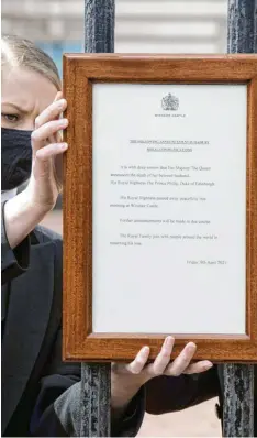  ?? Foto: Ian West/pa Wire, dpa ?? Freitagmit­tag in London: Eine Mitarbeite­rin hängt eine Tafel mit der Todesmitte­ilung an das Tor des Buckingham‰palasts.