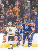  ?? The Canadian Press ?? Boston Bruins forward Brad Marchand, left, looks on as the Edmonton Oilers celebrate a goal during first-period NHL action in Edmonton on Thursday.