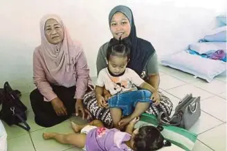  ?? [ FOTO POLIANA RONNIE SIDOM / BH ] ?? Siti Asmidah bersama anak dan ahli keluargany­a tinggal di Pusat Penempatan Sementara di Dewan PPR Batu Sapi, Sandakan.