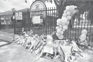  ?? — AFP photo ?? Floral tributes are seen outside the Banksia Road Public School a day after a car crash killed two pupils inside the school’s premises in Sydney’s west.