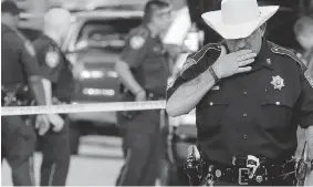  ?? DAVID J. PHILLIP/The Associated Press ?? Harris County Sheriff’s Department Sgt. D.J. Hilborn, right, walks away from the scene of a
multiple shooting Sunday in Houston. Eight people were found dead inside a home.