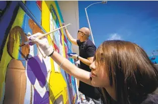  ?? NELVIN C. CEPEDA U-T ?? Leona Martinez, 14, and Mike Encarnacio­n were among a group of first-time mural painters who came out March 26 to take part in a community effort to revitalize businesses along Broadway.