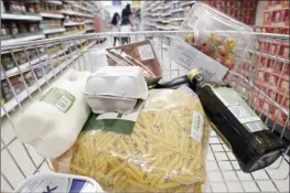  ?? AP photo ?? A basket of groceries are seen in a cart at a supermarke­t in London on Saturday. High food prices are pinching households across Europe, where food inflation is outpacing other major economies like the U.S., Japan and Canada. Some government­s have responded with formal price controls or loose agreements with supermarke­ts to keep costs down.