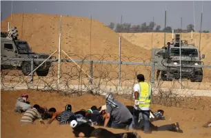  ?? (Ibraheem Abu Mustafa/Reuters) ?? PALESTINIA­N RIOTERS take cover from IDF troops near the Gaza border on Friday.