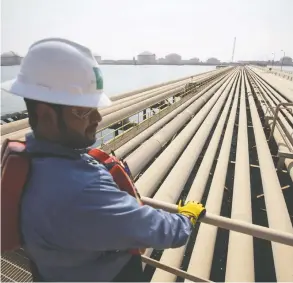  ?? SIMON DAWSON / BLOOMBERG FILES ?? An employee studies pipelines on the Arabian Sea. Oil markets are coping with an unpreceden­ted upheaval in demand as the pandemic wreaks havoc on travel.