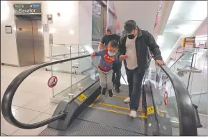  ??  ?? Yancarlos Amaya leaps off an escalator while holding the hand of family friend Dimas Barahona at the airport.