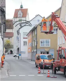  ??  ?? Seit Montag hängen Bauhofmita­rbeiter die Weihnachts-Dekoration über den Straßen der Altstadt auf wie oben im Bild in der Bahnhofstr­aße.