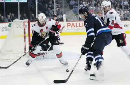  ?? TREVOR HAGAN /THE CANADIAN PRESS ?? The Winnipeg Jets’ Adam Lowry drives to the net between the Senators’ Erik Karlsson and Dion Phaneuf during the first period in Winnipeg on Sunday. The Senators were outshot and completely outplayed by the Jets.